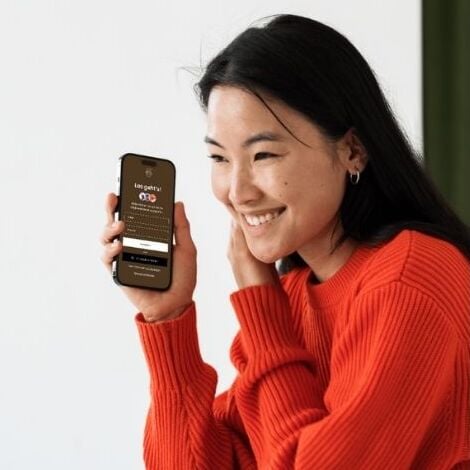Lächelnde Frau mit einer digitalen Hochzeitseinladung auf dem Smartphone
